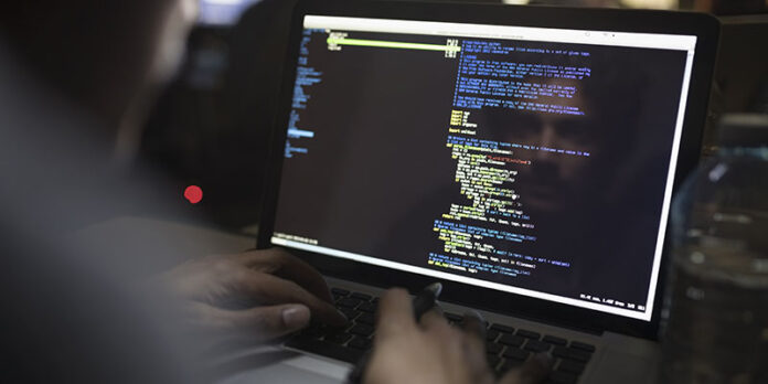 Reflection of male hacker coding working hackathon at laptop