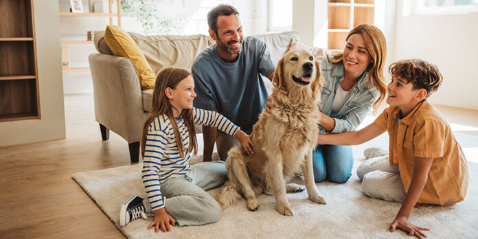 Family with two children relaxing in living room. playing with golden retriever dog after moving into new home.